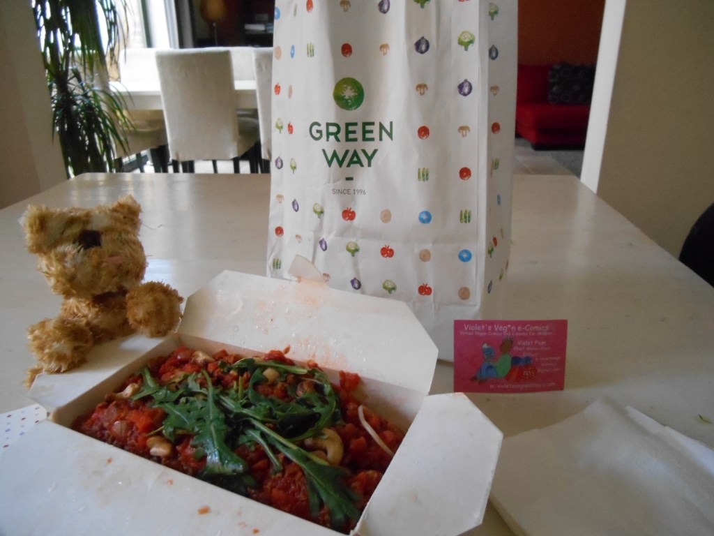 Take away food in paper bag from Greenway vegetarian restaurant.  Vegan Spaghetti bolognese.  In the cardboard box with a toy cat.